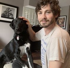 a man sitting on top of a couch holding a black and white dog in his lap