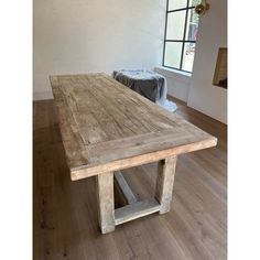 a large wooden table sitting on top of a hard wood floor next to a window