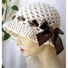 a white crocheted hat with brown bows on it's brimming