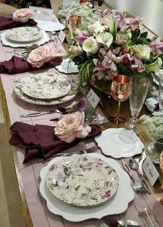 the table is set with plates, silverware and flowers