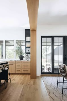 an open kitchen and dining area with wooden floors, black doors, and white walls