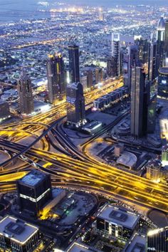 an aerial view of a city at night with many lights and roads in the foreground