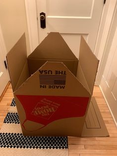 an open cardboard box sitting on the floor in front of a white door with black and red stripes