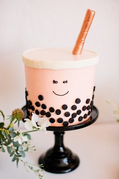 a cake decorated with polka dots and a smiling face on top is sitting on a black stand