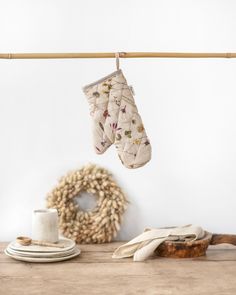 two oven mitts hanging from a clothes line with a wreath in the back ground