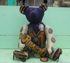 a teddy bear sitting on top of a wooden bench next to some buttons and coins