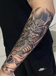 a man with a tattoo on his arm is holding a knife and wearing a helmet