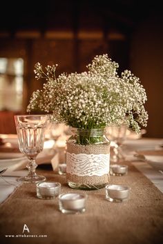 a vase filled with baby's breath sitting on top of a table next to candles