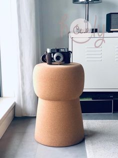 a camera sitting on top of a stool in front of a window next to a lamp