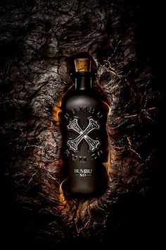 a black bottle with skulls on it sitting in the middle of a dark background,