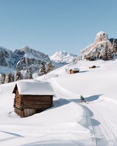 a person riding skis on top of a snow covered slope next to a cabin