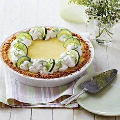 a pie with cucumbers and whipped cream on top is sitting on a table