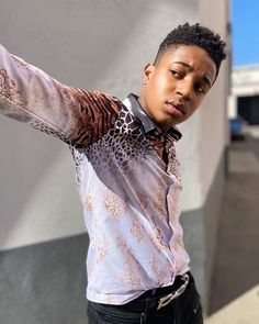 a young man wearing a shirt and black pants posing for the camera with his hand on his hip