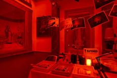 a room with red lighting and pictures hanging from the ceiling, in front of a window