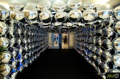 a room filled with lots of shiny silver balls on the ceiling and walls, along with black carpeting