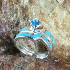 This beautiful Sterling Silver Ring Set, as part of the Arizona Blue Collection features Kingman Turquoise with a Blue Topaz. Engagement Ring Width: Top 5/8"; Shank 1/8" Band Width: 1/4"; Shank 1/8" The ring is designed by David Rosales, one of the finest contemporary Southwest Artists in the world. He is the founder and co-owner of Supersmiths, Inc. of Gallup, NM. Each ring is custom made and carries a lifetime guarantee. Turquoise Sterling Silver Jewelry With Center Stone, Blue Turquoise Ring With Gemstone Accents In Sterling Silver, Sterling Silver Turquoise Ring With Gemstone Accents, Blue Turquoise Gemstone Ring Fine Jewelry, Blue Turquoise Gemstone Ring In Fine Jewelry Style, Blue Opal Inlay Ring For Anniversary, Blue Opal Ring With Inlay For Anniversary, Blue Turquoise Gemstone Ring, Anniversary Blue Opal Ring With Inlay