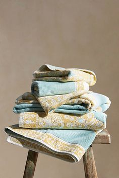 a stack of folded towels sitting on top of a wooden stool