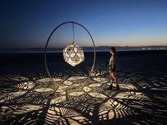 a woman standing in front of a sculpture on the beach