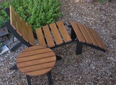 two wooden benches sitting next to each other in front of some bushes and plants on the ground