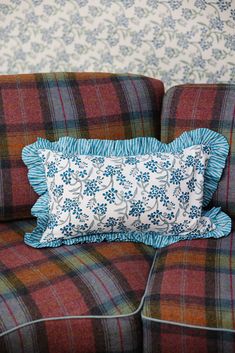 a plaid couch with a blue and white pillow sitting on it's back end