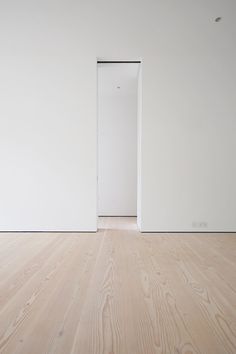 an empty room with white walls and wood floors