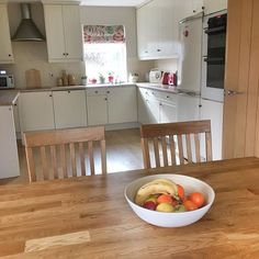 a bowl of fruit sitting on top of a wooden table in front of an oven