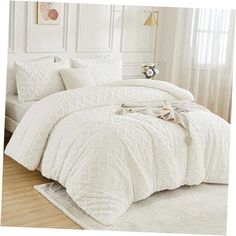 a bed with white comforter and pillows in a room