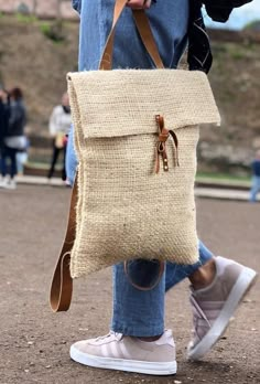 a person wearing jeans and sneakers carrying a bag