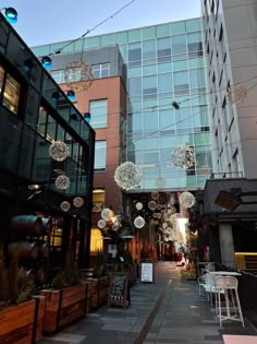 an alley way with lots of lights hanging from the ceiling and plants growing on the sidewalk