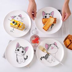 three plates with cartoon cats on them, one has food and the other has bread