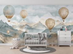 a baby's room decorated in neutral tones with hot air balloons flying over the mountains