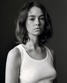 a black and white photo of a woman in a tank top looking at the camera