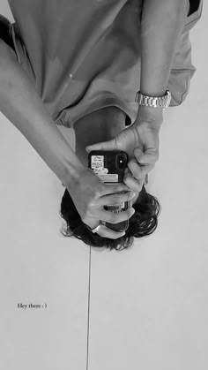 black and white photograph of a woman holding a cell phone in her right hand while looking down at the ground