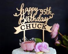 a cake with a happy 35th birthday sign on it and pink flowers in the foreground