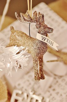 a gold reindeer ornament hanging from a string with a name tag on it