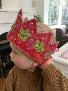 a young boy wearing a pink crown with green flowers on it