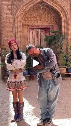 a man standing next to a woman in front of a building