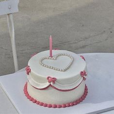 a heart shaped cake sitting on top of a table next to a white plate with a pink ribbon