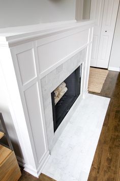 an empty fireplace with white paint and wood floors