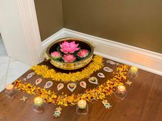 there is a bowl with flowers and candles on the floor in front of some decorations