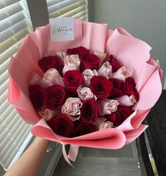 a bouquet of red and white roses with a note on it