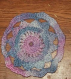 three crocheted coasters sitting on top of a wooden table