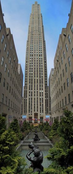 a statue in the middle of a courtyard with tall buildings behind it and trees around