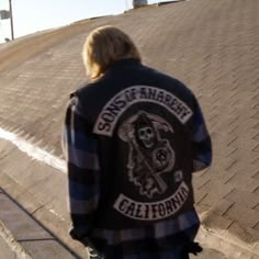 a young man riding a skateboard down the side of a brick road next to a parking lot