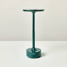 a green table lamp sitting on top of a white surface