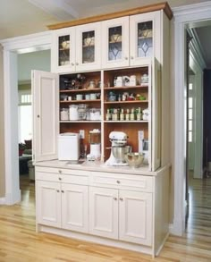 a kitchen with white cabinets and wooden floors