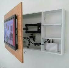 a television mounted to the side of a white wall next to a shelf with wires