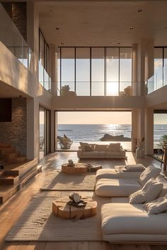 a living room with white furniture and large windows overlooking the ocean in front of an open floor plan