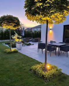 an outdoor dining area is lit up at night with yellow lights on the table and chairs