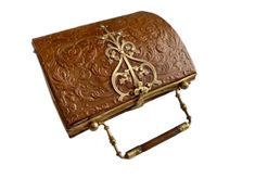 an ornate brown leather box with gold accents on the front and sides, sitting on a white background